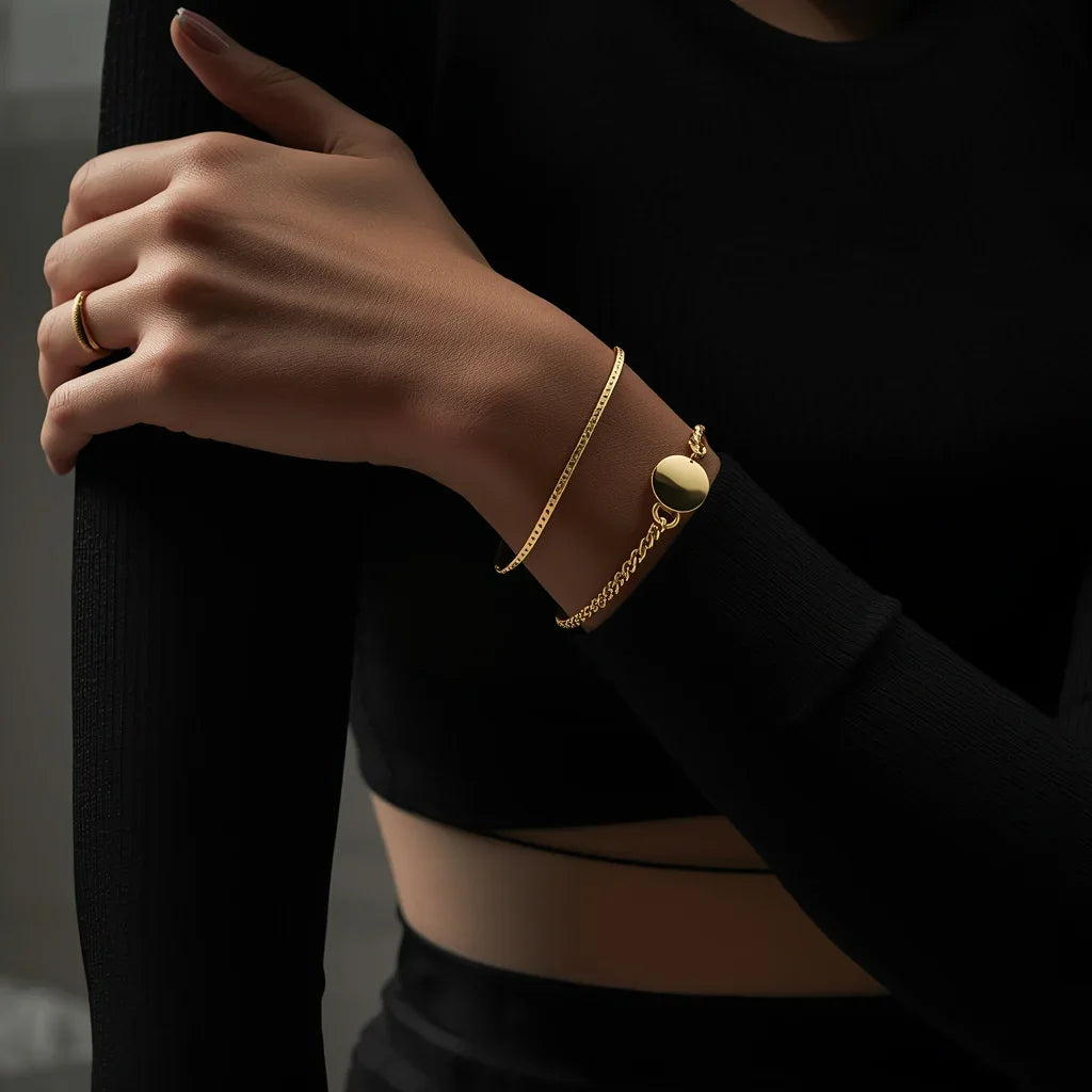 Woman wearing layered gold bracelets and ring on wrist and hand, black long sleeve top