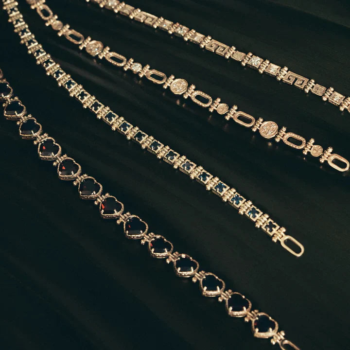 Four elegant gold and silver gemstone bracelets with varying designs on a dark surface.