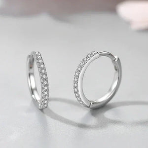 Pair of silver hoop earrings with clear stones on a light gray background