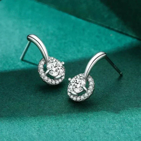 Silver earrings with clear gemstones on a green fabric background