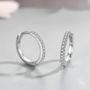Pair of silver hoop earrings with clear gemstones on a light gray background