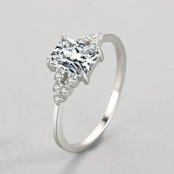 Elegant silver ring with a rectangular clear gemstone and small accent stones on band