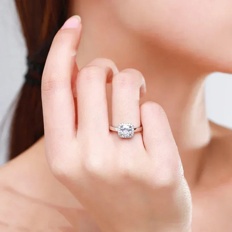 Woman wearing elegant silver halo engagement ring with cushion-cut center stone