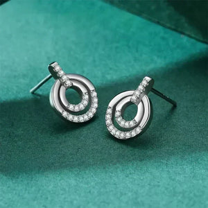 Silver earrings with circular design on a teal fabric background