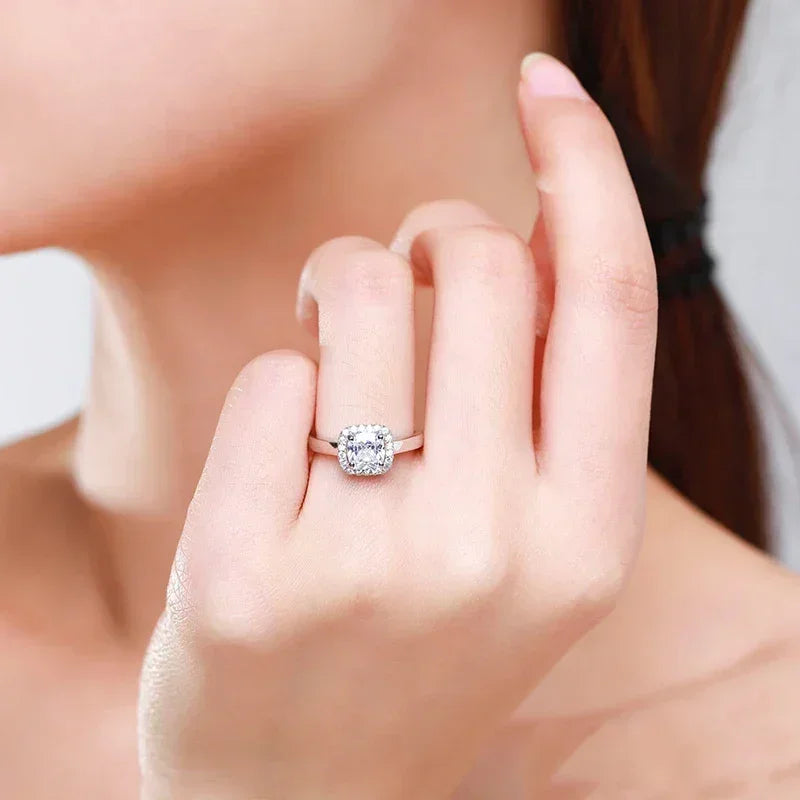Woman wearing a sparkling cushion-cut silver engagement ring on her finger