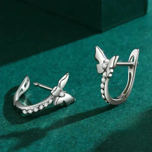 Silver earrings with butterfly design on a green background