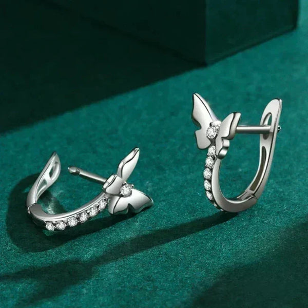 Silver earrings with butterfly design on a green background