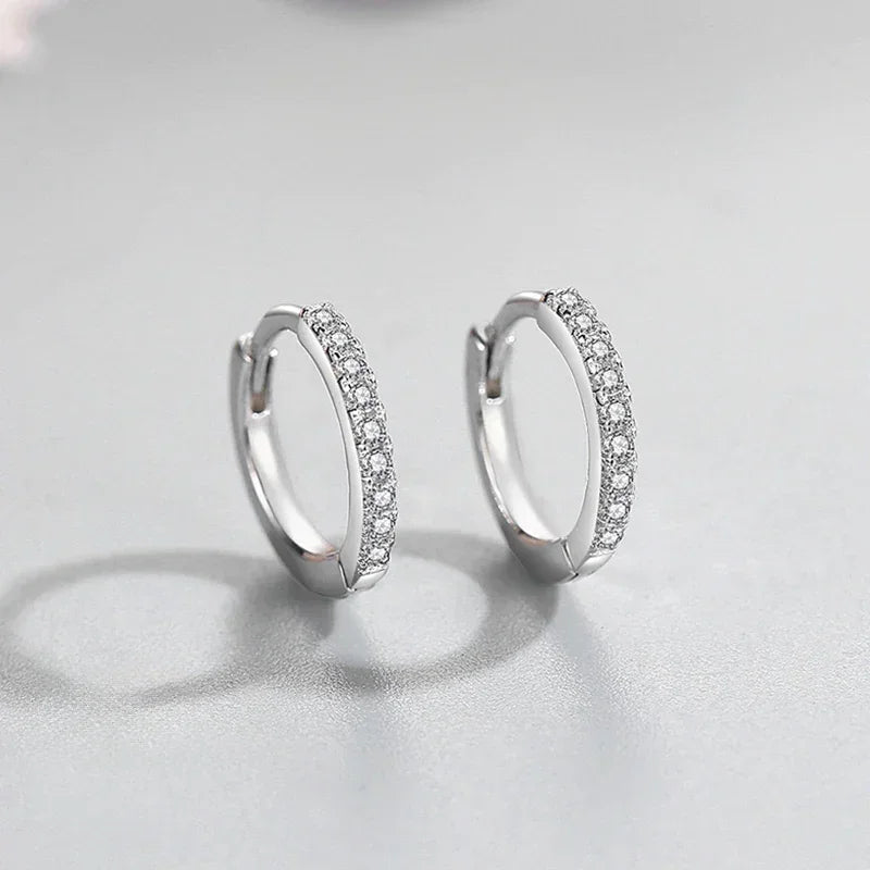 Sterling silver hoop earrings with pavé white stones on a light background