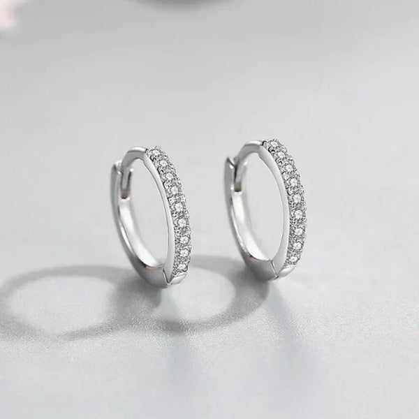 Silver hoop earrings with embedded stones on a light gray background