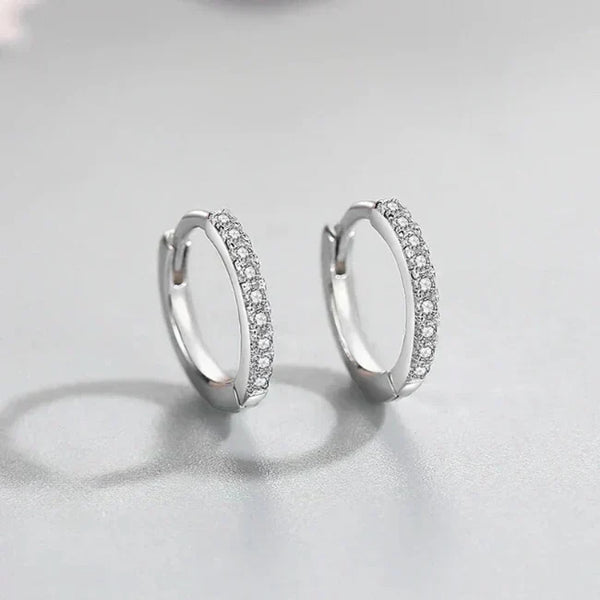 Silver hoop earrings with embedded stones on a light gray background