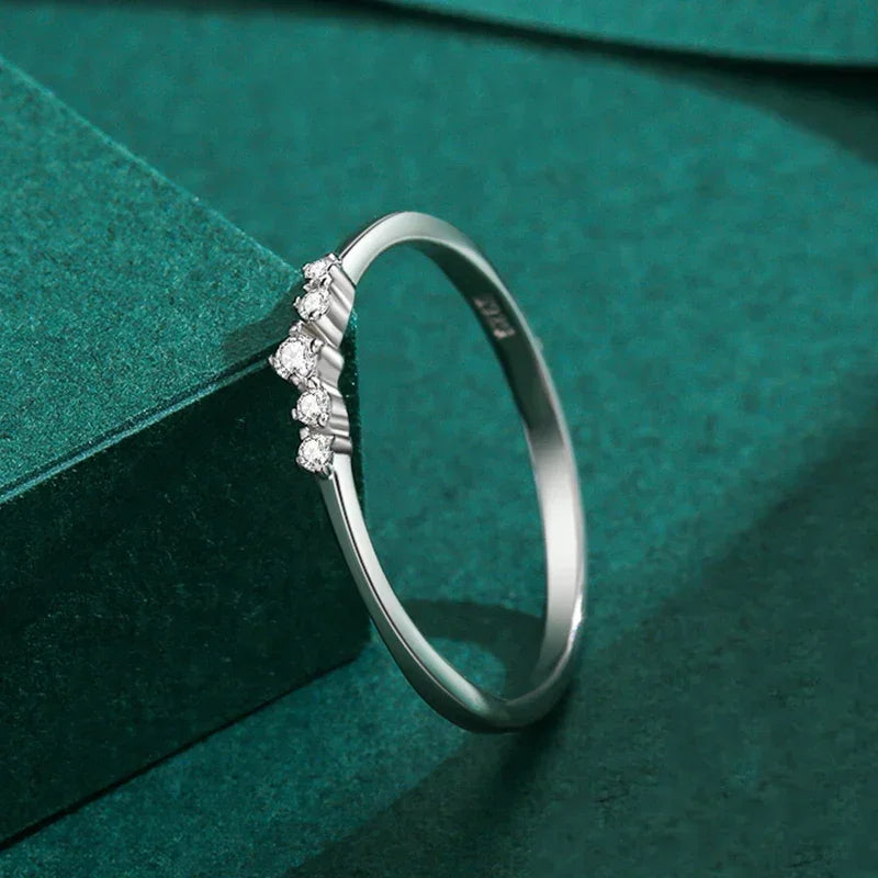 Sterling silver ring with five small round gemstones on green textured background