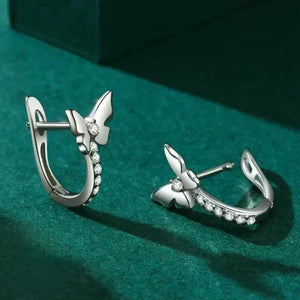 Silver earrings with butterfly design on a green background