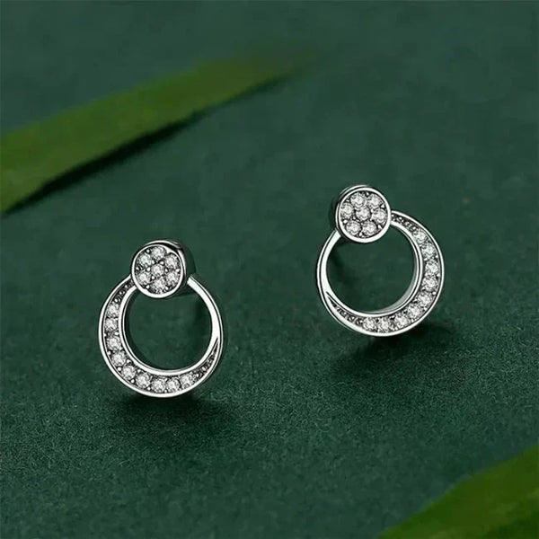 Pair of silver hoop earrings with clear stones on a green background