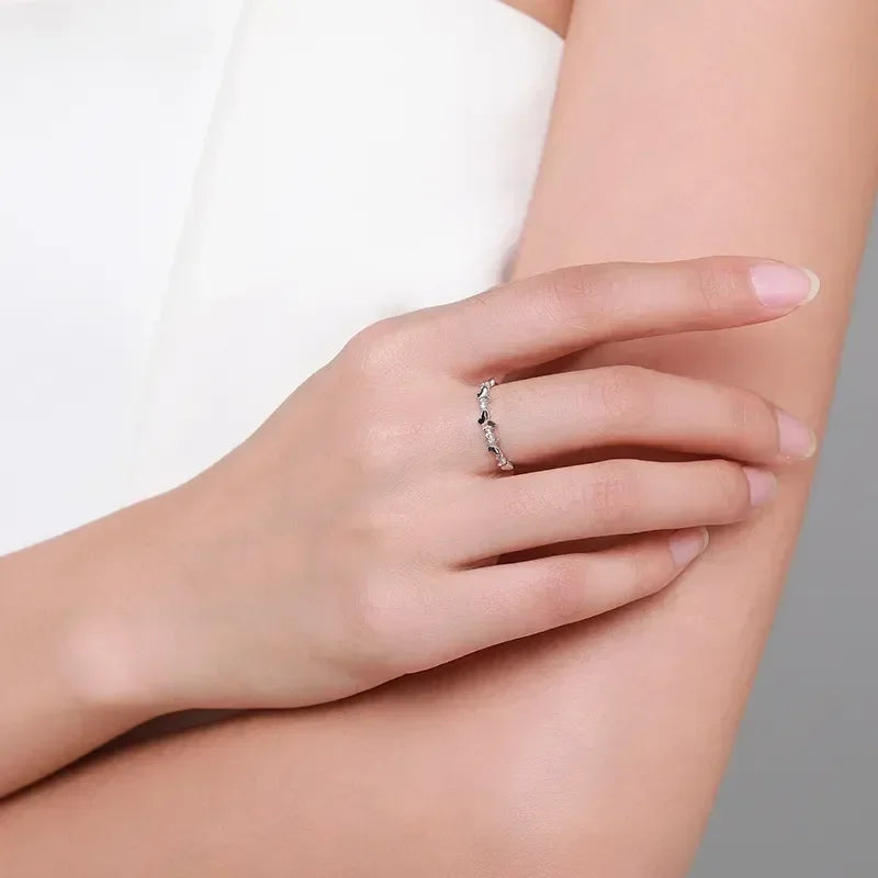 Delicate 925 silver band ring with small stones on woman's hand against neutral background