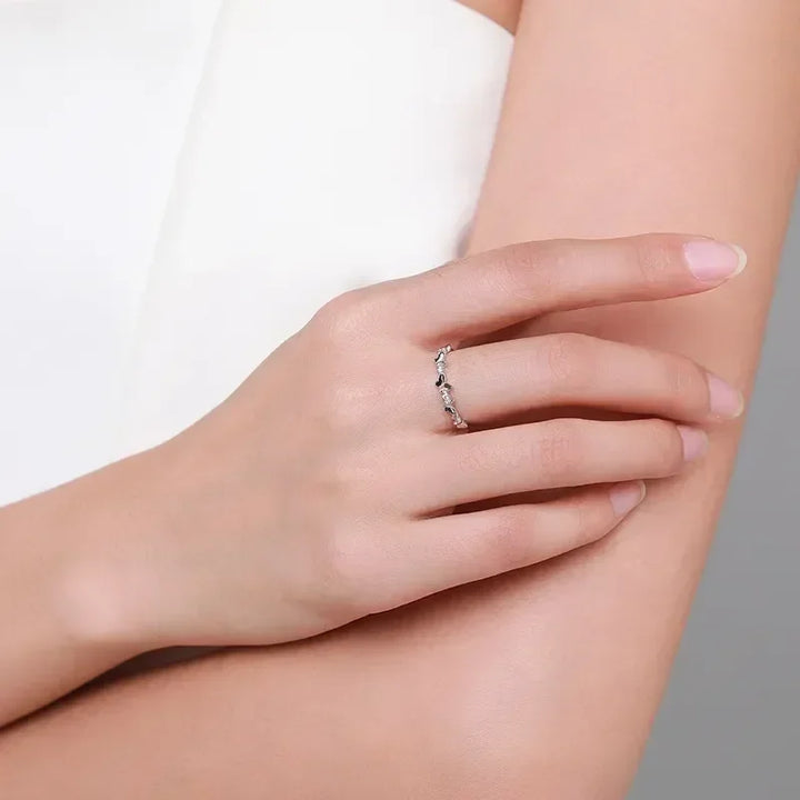 Delicate 925 silver band ring with small stones on woman's hand against neutral background