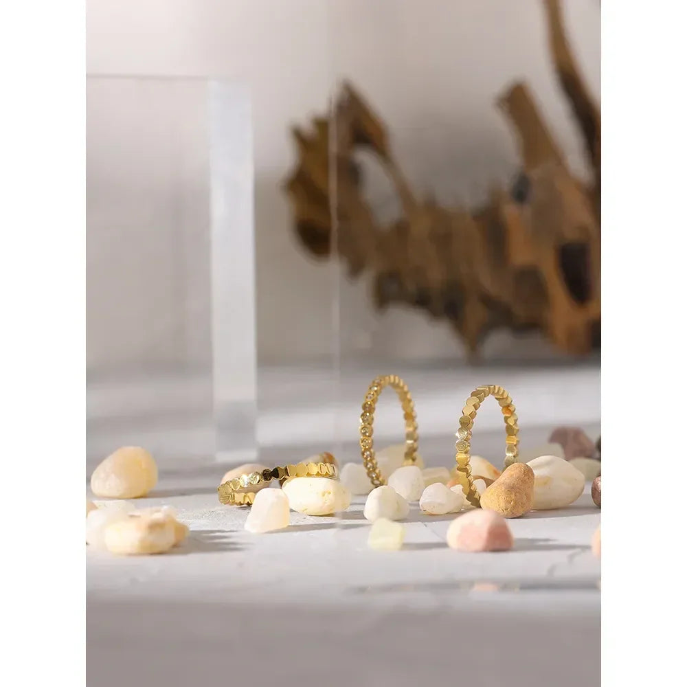 Gold-plated silver textured rings on white stones, minimalist jewelry display