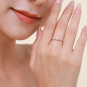 TM & CO. JEWELS - Woman wearing delicate 925 silver ring with small gemstones on finger, close-up.
