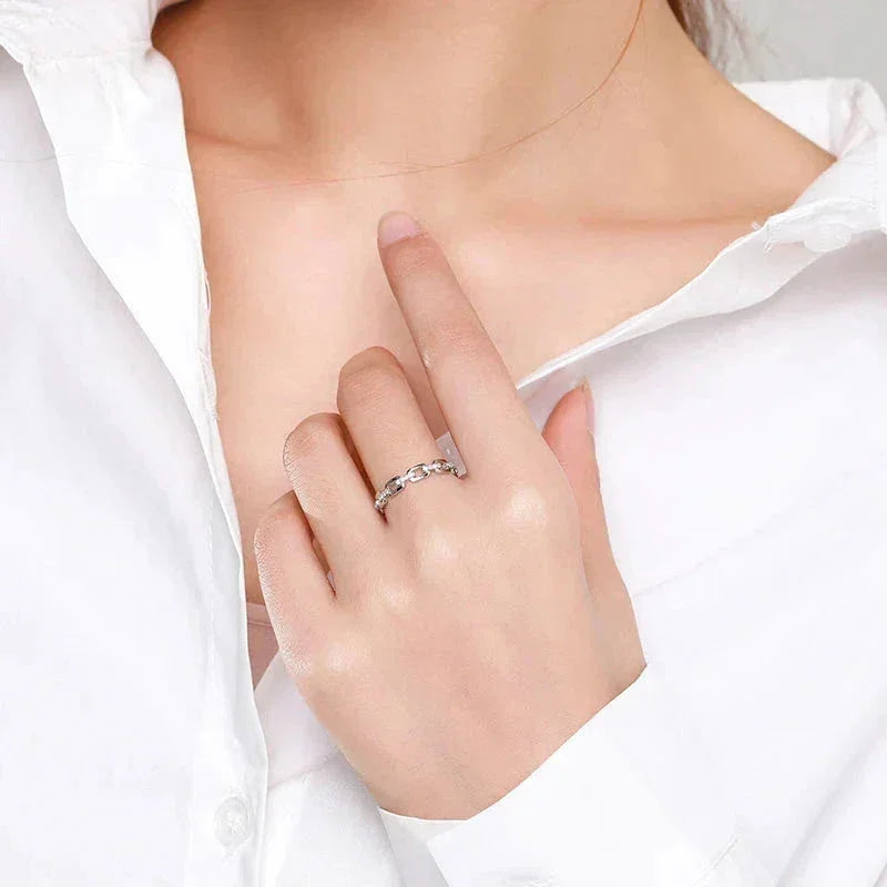 Woman wearing a 925 silver chain link ring, hand near collar, white shirt background