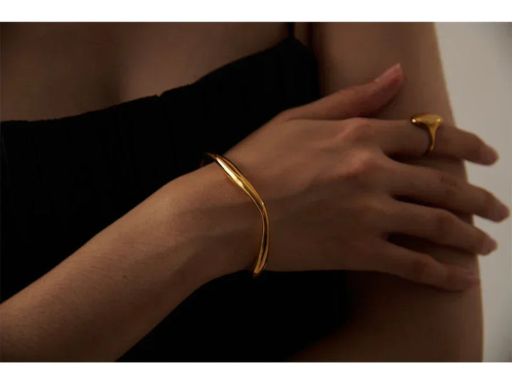 Woman wearing elegant 18K gold-plated bangle bracelet and matching gold ring
