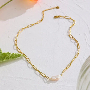 Gold chain bracelet on a light surface with a leaf
