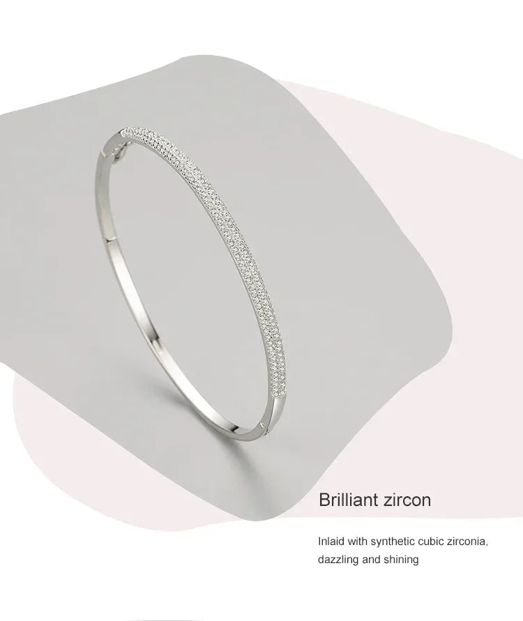 Elegant silver bangle bracelet with sparkling cubic zirconia stones on a light backdrop.