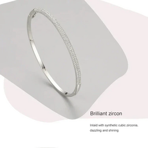 Elegant silver bangle bracelet with sparkling cubic zirconia stones on a light backdrop.