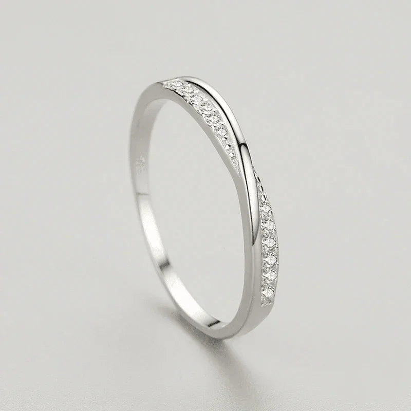 Sterling silver women's ring with a wavy band and pavé set clear stones on a light background