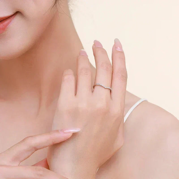 Elegant woman wearing a thin silver ring with small stones on her finger, close-up.