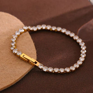 Gold bracelet with clear stones on a brown surface, featuring the 'Vogue' brand.