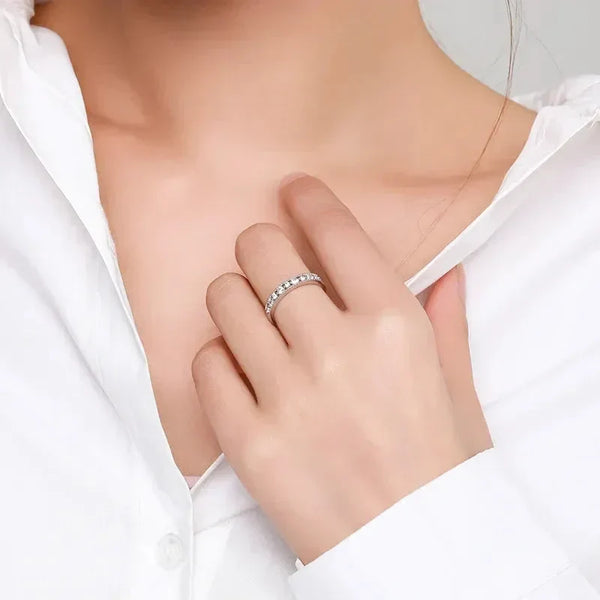 Woman wearing a white shirt and a silver band ring with clear gemstones on her finger