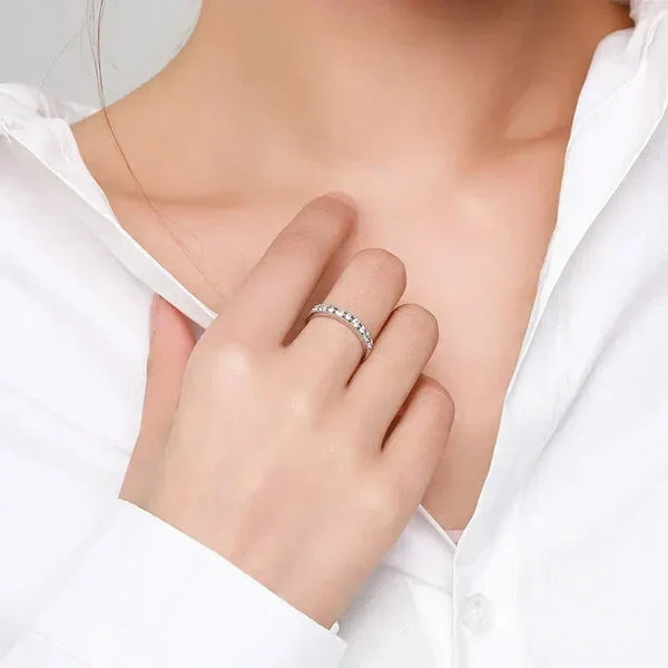 Woman wearing a silver eternity band with clear stones on her finger, white blouse