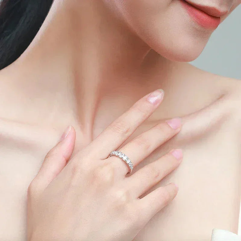 Woman wearing elegant 925 silver eternity band ring with sparkling gemstones on her finger