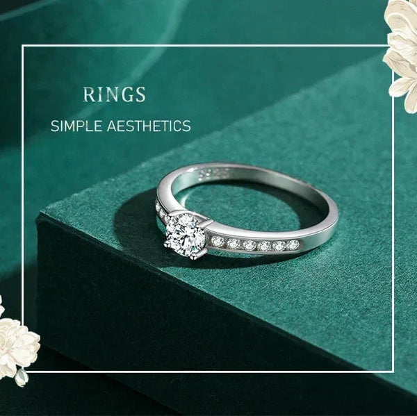 Silver ring with small diamonds on a green surface with white flowers.