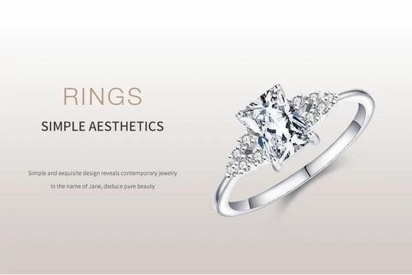 Elegant silver engagement ring with a rectangular clear center stone and side accents.