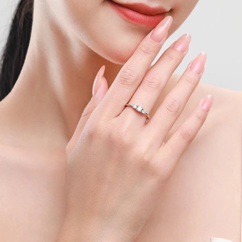 Woman wearing a delicate silver ring with three clear gemstones on her finger