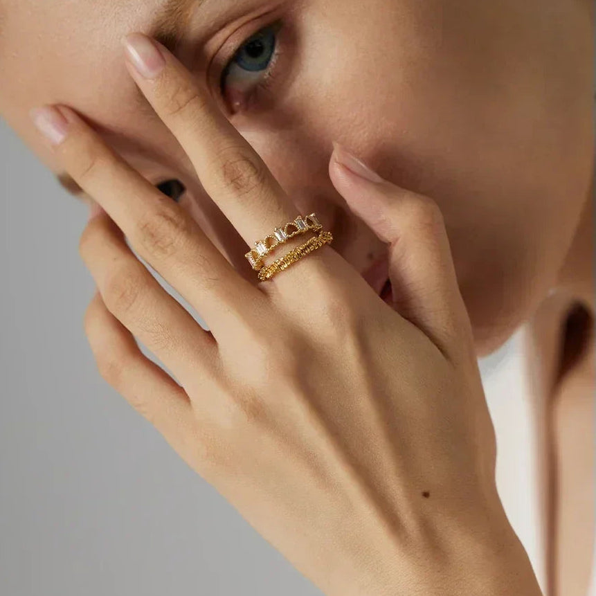 Close-up of a hand wearing a gold ring with a gray background