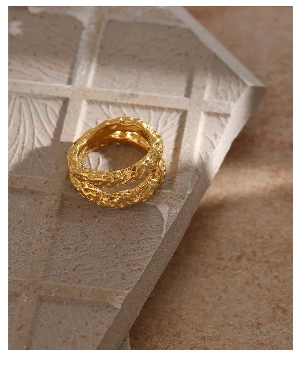 Textured gold-plated ring with organic design on stone surface, elegant women's jewelry