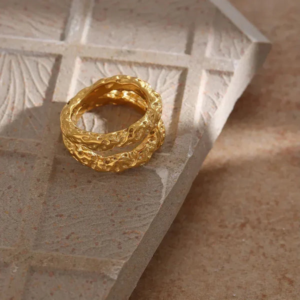 Textured gold-plated ring with organic design on stone surface, elegant women's jewelry