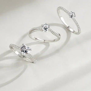 Sterling silver ring with round-cut solitaire and pave accent stones, elegant minimalist design.