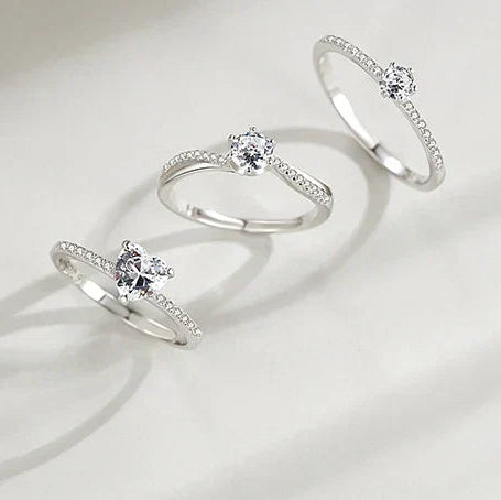 Sterling silver ring with round-cut solitaire and pave accent stones, elegant minimalist design.