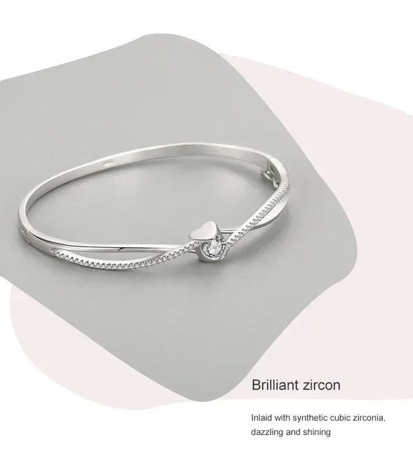Sterling silver bracelet with heart and cubic zirconia centerpiece on gray background