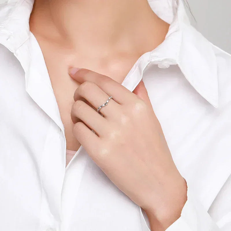 Woman wearing a delicate 925 silver ring with small round stones, styled with a white shirt.
