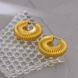 Textured gold-plated hoop earrings on clear textured glass, modern jewelry for women