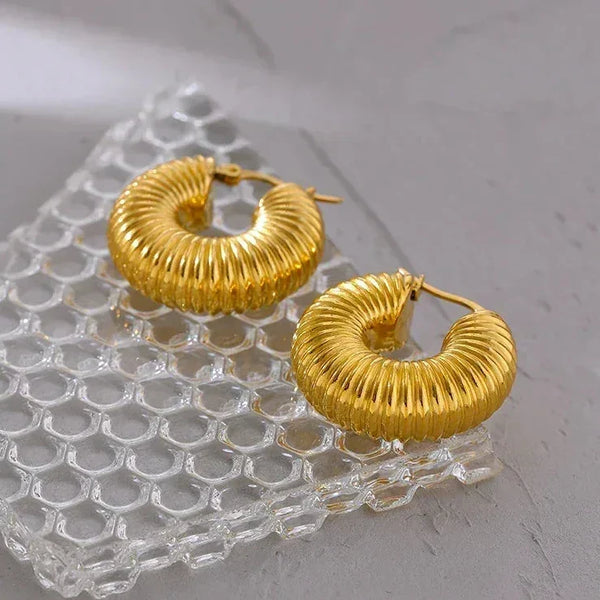Textured gold-plated hoop earrings on clear textured glass, modern jewelry for women