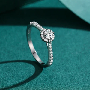 Sterling silver ring with round center cubic zirconia and pavé band on white background