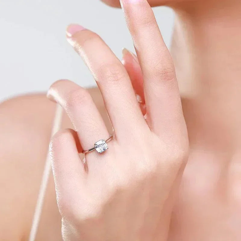 Silver solitaire ring with cushion-cut gemstone on woman's hand