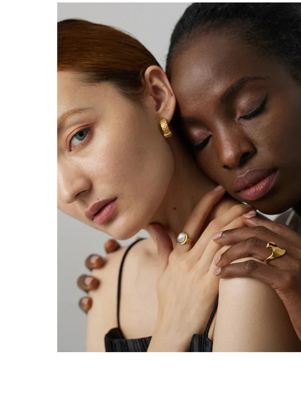 Two women showcasing gold-plated earrings and rings with elegant minimalist design.