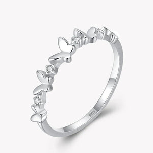 Silver ring with butterfly designs and small diamonds on a white background