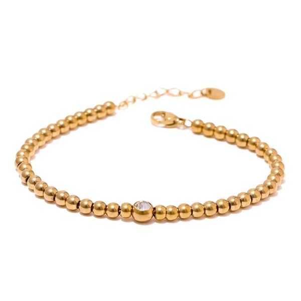 18K gold-plated beaded bracelet with single clear gem on geometric display