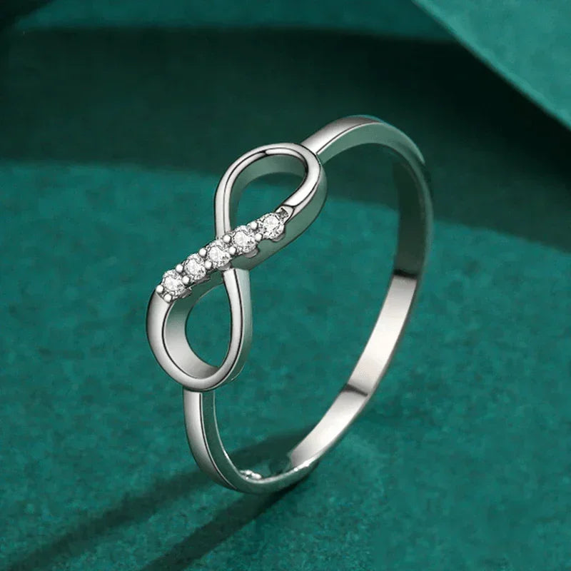 925 silver infinity ring with sparkling stones on a green background
